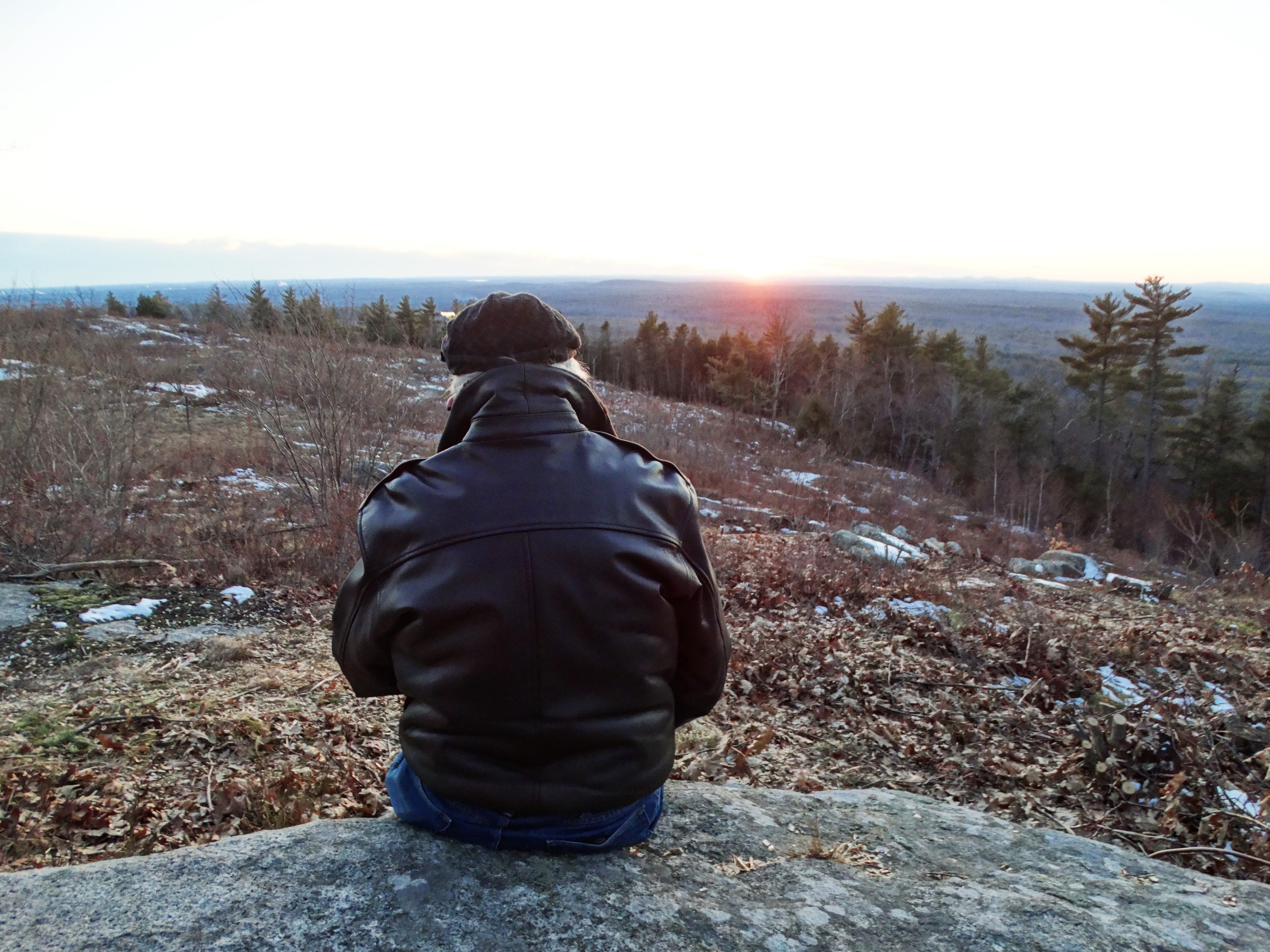 view from behind of a person sitting on a large rock on the Mount Agamenticus summit