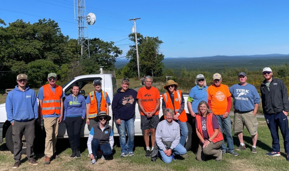 group of staff and volunteers standing at summit of Mount Agamenticus