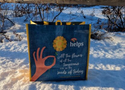Bright blue Hannaford reusable Community Bag on snow against fence at Mount Agamenticus